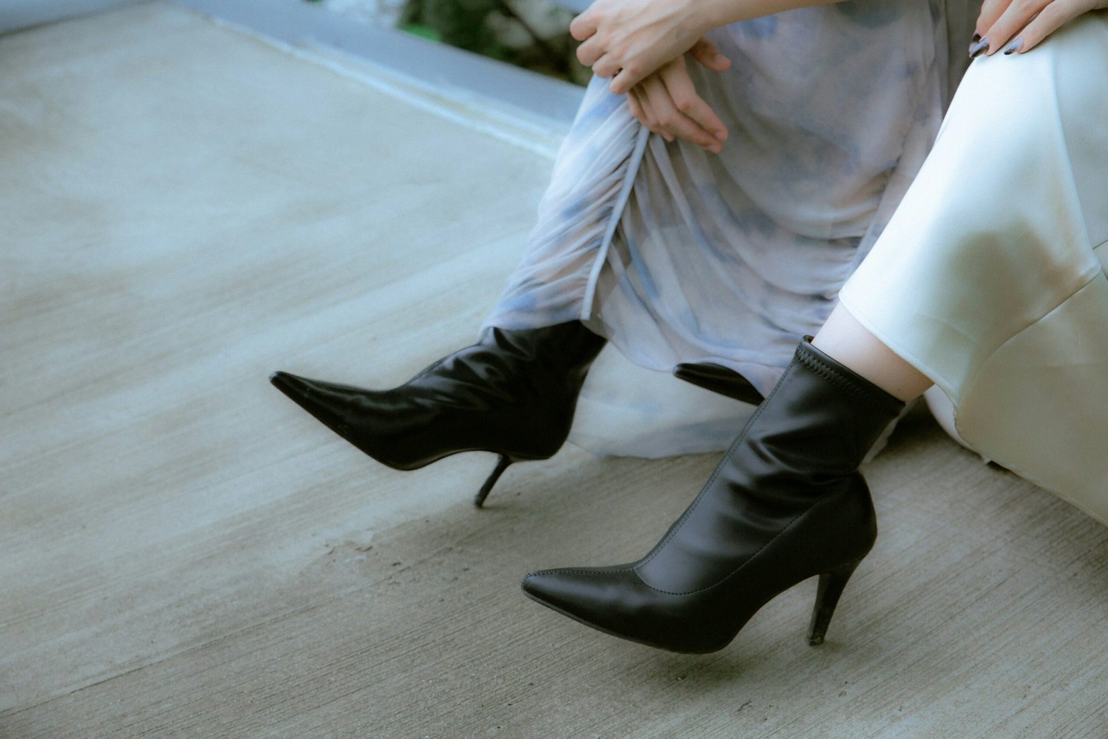 Woman wearing black pointed-toe ankle boots with heels paired with a flowing dress for a chic everyday look.